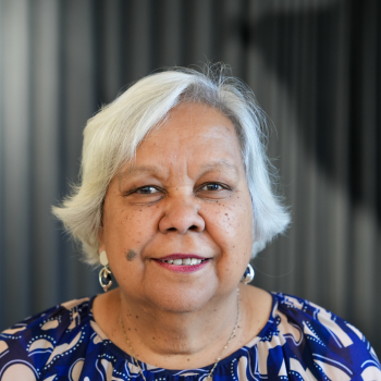Older woman with short white hair smiling against softly blurred indoor background